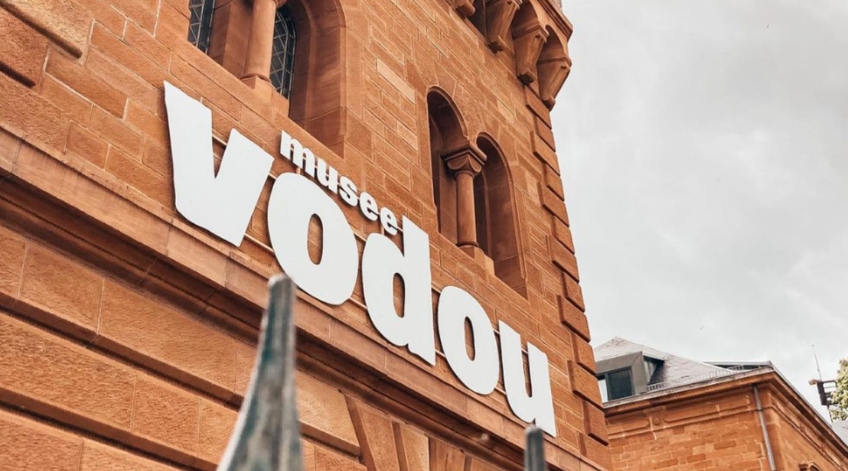 View of Vodou Museum. The Vodou Museum is a captivating institution that immerses visitors in the rich and mysterious world of Vodou, a spiritual and cultural practice with roots in Haiti. The museum's exterior exudes a bright orange color and a sign with large white letters "Vodou Musee".