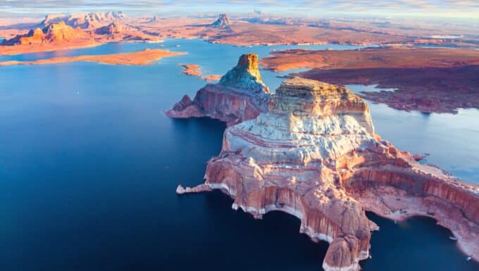 Lake Powell in Arizona. The image captures the expansive azure waters of the lake, framed by towering sandstone cliffs that create a stunning contrast against the clear blue sky.