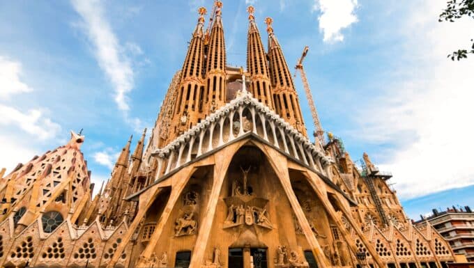 Sagrada Familia basilica in Barcelona. The image showcases the intricate and soaring spires of this masterpiece. The façade is adorned with intricate sculptures and religious symbolism. The warm sunlight bathes the basilica