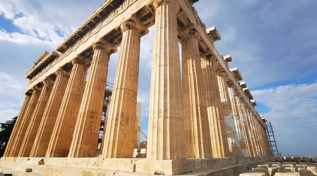 A close-up view of the Acropolis in Athens, Greece, devoid of people and under cloudy skies. The classical columns and intricacies of the ancient Greek architecture are visible, emphasizing the historical significance of the site.