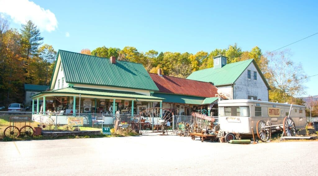 An image depicting the exterior of Rusty Cobweb Antiques business in Bethel, New Hampshire, USA. The photograph captures the facade of the antique store, featuring signage and architectural details. The surroundings suggest a modest and rustic setting.