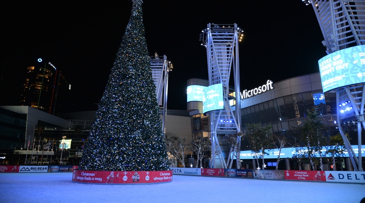 A photograph capturing an ice skating field devoid of people during the night, centrally featuring a large Christmas tree in Los Angeles.