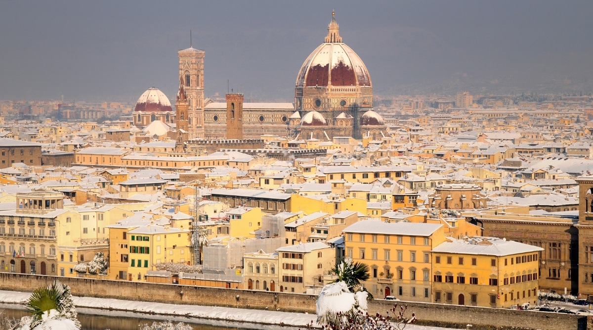 The Cathedral of Santa Maria del Fiore in Florence depicted after a snowfall during winter, as viewed from Piazzale Michelangelo. The image captures the iconic cathedral and its surroundings covered in snow. The architectural features of the cathedral, including the iconic dome and Giotto's Campanile, are visible against the winter landscape.