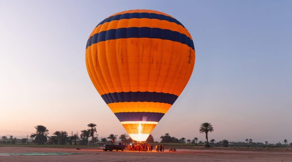 A photograph depicting the inflation process of a hot air balloon prior to liftoff. The image captures the balloon gradually expanding as it fills with air.