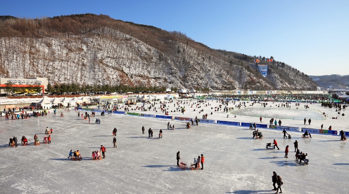 The image captures scenes from the Hwacheon Mountain Trout Festival in Gangwon-do, Korea. Participants engage in the activity on a frozen body of water.The photograph features individuals participating in trout fishing. 