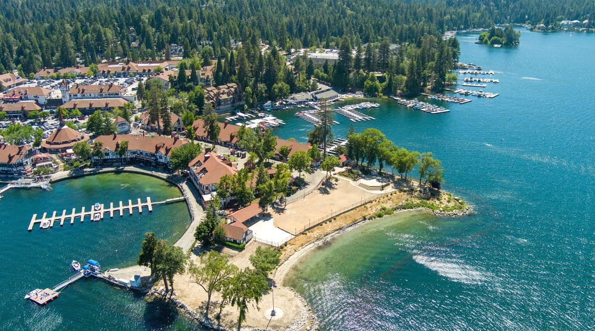 A photograph capturing Lake Arrowhead, a reservoir in the San Bernardino Mountains of Southern California. The image showcases the lake's expanse surrounded by forested landscapes. Boats and recreational activities are visible on the water.