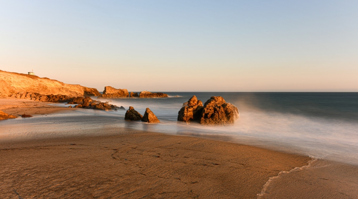 A view of Leo Carrillo Beach in Malibu, featuring a stretch of sandy shore, the ocean, and small rock formations.