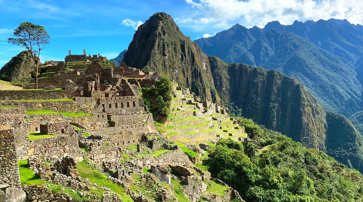 The photograph depicts Machu Picchu, a renowned archaeological site situated in Peru. The image captures the panoramic view of the ancient Incan citadel nestled amidst the Andes Mountains. Machu Picchu's distinct architectural structures, including terraces and stone buildings, are visible in the foreground.