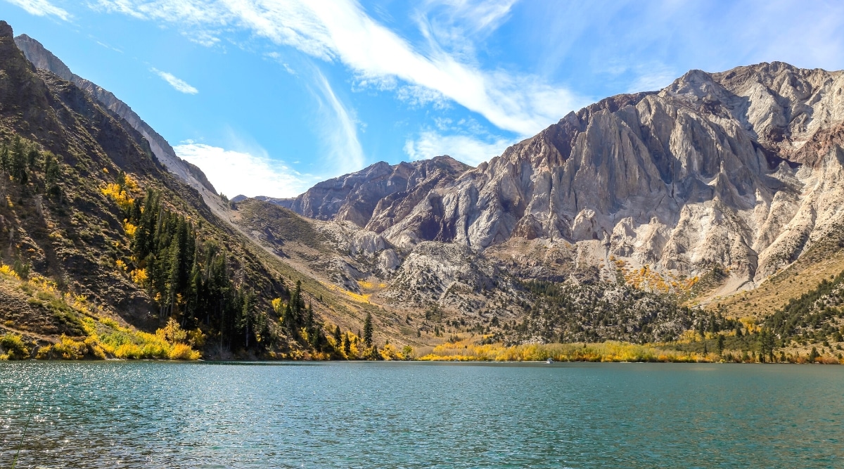A photograph depicting the landscape of Mammoth Lakes. The image showcases the serene lakes surrounded by mountainous terrain in a natural setting. The weather conditions appear clear, providing a neutral backdrop for the scenery.
