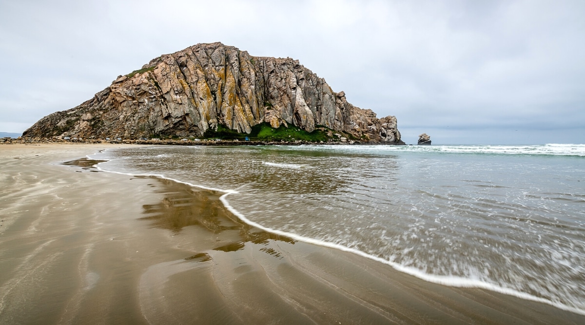 A direct view of Morro Bay Beach in San Luis Obispo. The image captures the beach's expanse and shoreline, featuring the Pacific Ocean meeting the sandy coastline.