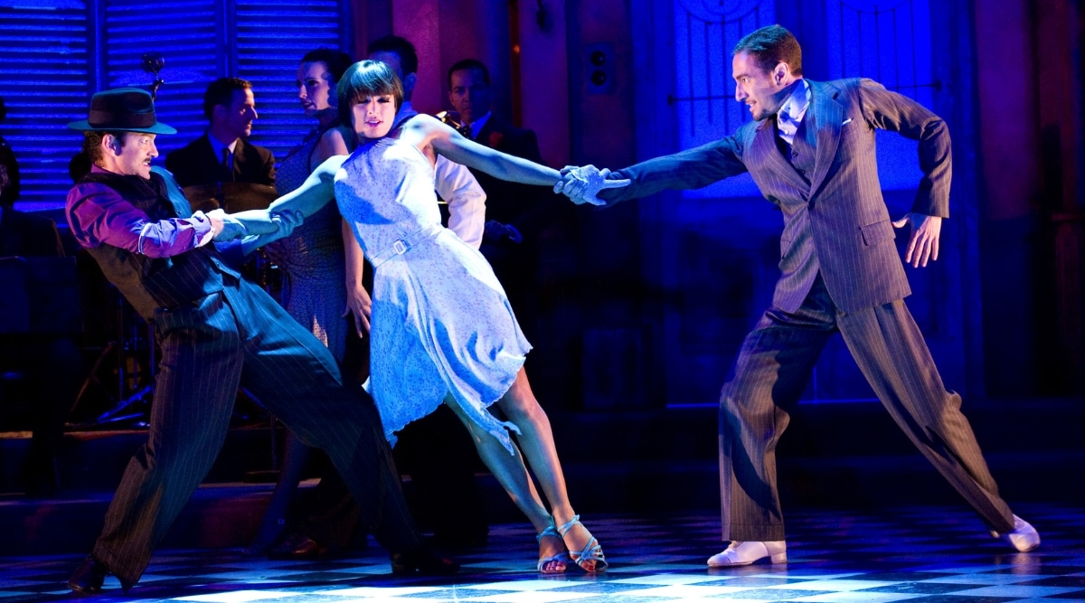 A photograph capturing a scene from Pretty Woman: The Musical in Los Angeles. The image features performers on stage, including a woman and several men, in the midst of a production.