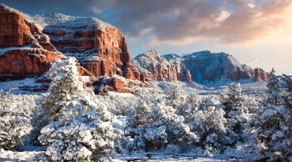 A photograph capturing the winter landscape around Sedona, Arizona, featuring snowy mountains and rocks.