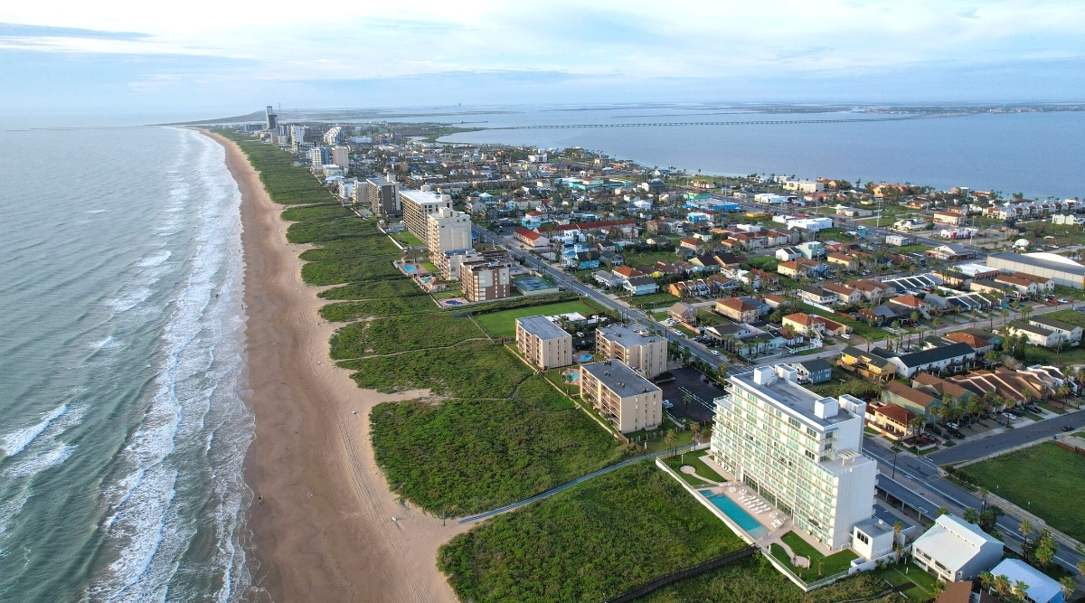 A drone view capturing South Padre Island, Texas. The image showcases the island's geographical features, including its coastline and surrounding areas. The scene provides a comprehensive overview of the landscape, with neutral tones and clear visibility.