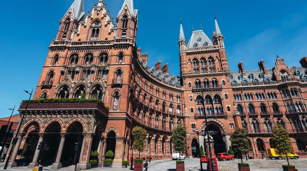 A photograph capturing the exterior of St. Pancras in London. The image showcases the architectural features of the iconic structure against a neutral sky backdrop. 