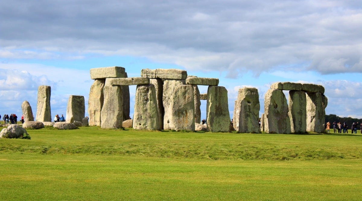 A photograph depicting Stonehenge, a prehistoric monument located in England. The image showcases the iconic arrangement of large standing stones set against the surrounding landscape. Stonehenge is characterized by its concentric circles and the placement of the massive stones, forming a distinctive and ancient architectural structure.