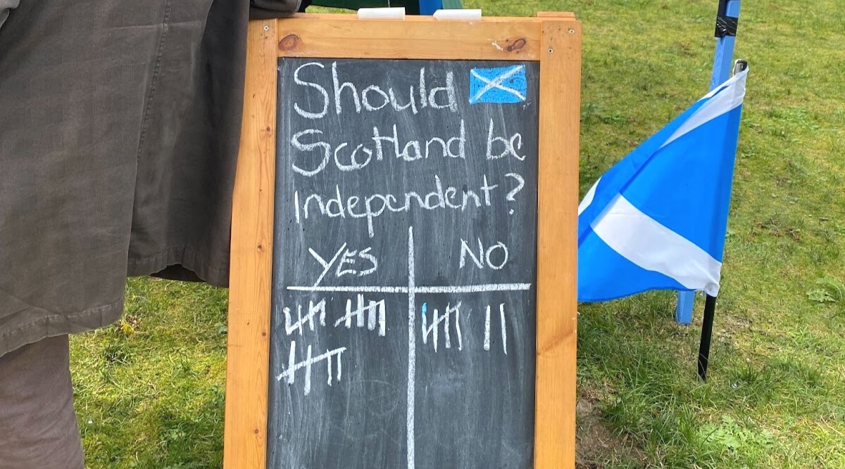 A wooden board designed for drawing with chalk, featuring the question 'Should Scotland be independent? Yes/No?' written in chalk. The background displays the flag of Scotland. 