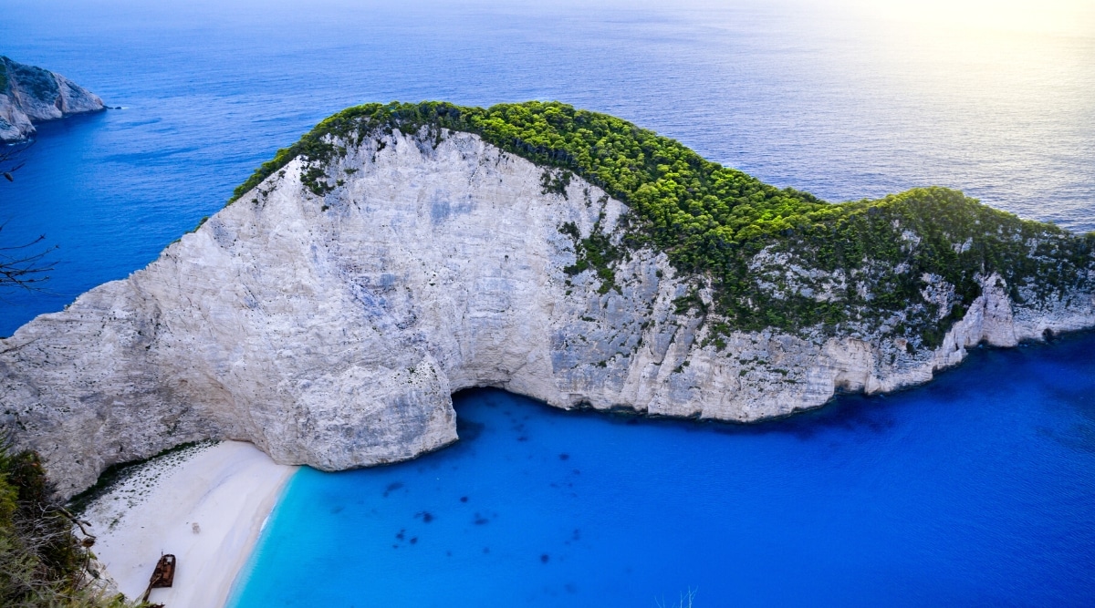 A photograph capturing Navagio Beach in Zakynthos, Greece. The image showcases the iconic beach framed by steep cliffs and the turquoise waters of the Ionian Sea. 