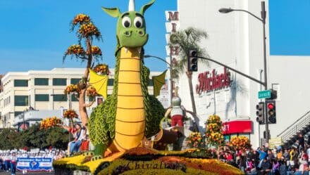 A photograph capturing a float featuring a large dragon during the Rose Parade in Los Angeles. The image showcases the intricately designed float adorned with flowers and other decorative elements, moving along the parade route. Spectators lining the streets are seen observing the elaborate presentation.