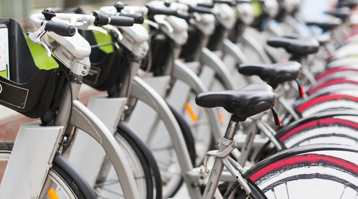 A photograph capturing a row of parked bicycles available for rent on a sidewalk.