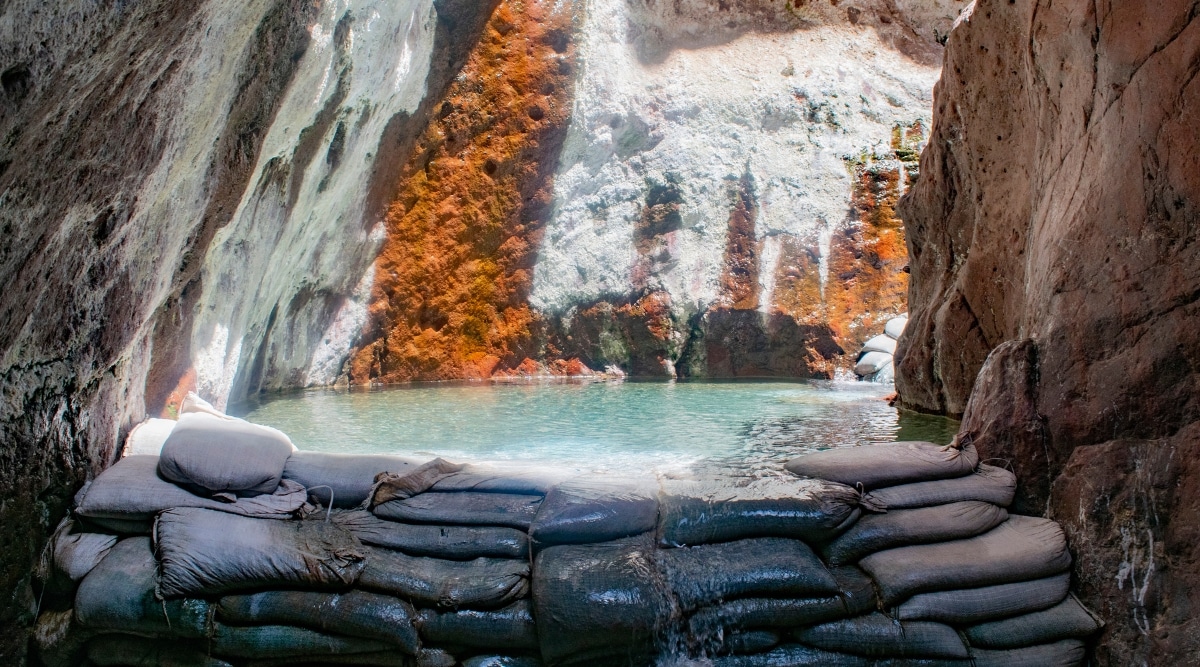 A photograph depicting Arizona Hot Springs in a desert setting. The image captures the natural hot springs surrounded by rocky terrain. The hot springs are integrated into the rocky landscape, providing a contrast between the warm water and the surrounding geology.