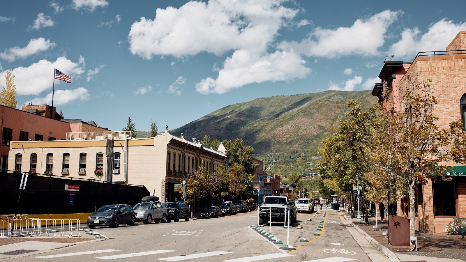 A photograph depicting the town of Aspen, Colorado. The image captures the town's surroundings, characterized by mountainous terrain and evergreen trees.