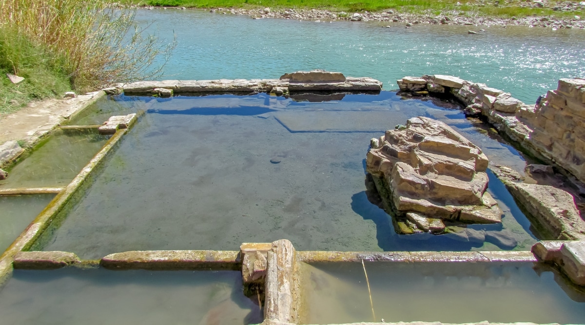 A visual depiction of Boquillas Hot Springs in Texas, showcasing a square-shaped rock formation partially submerged in water. The image provides a straightforward view of the geological feature, devoid of specific details. 