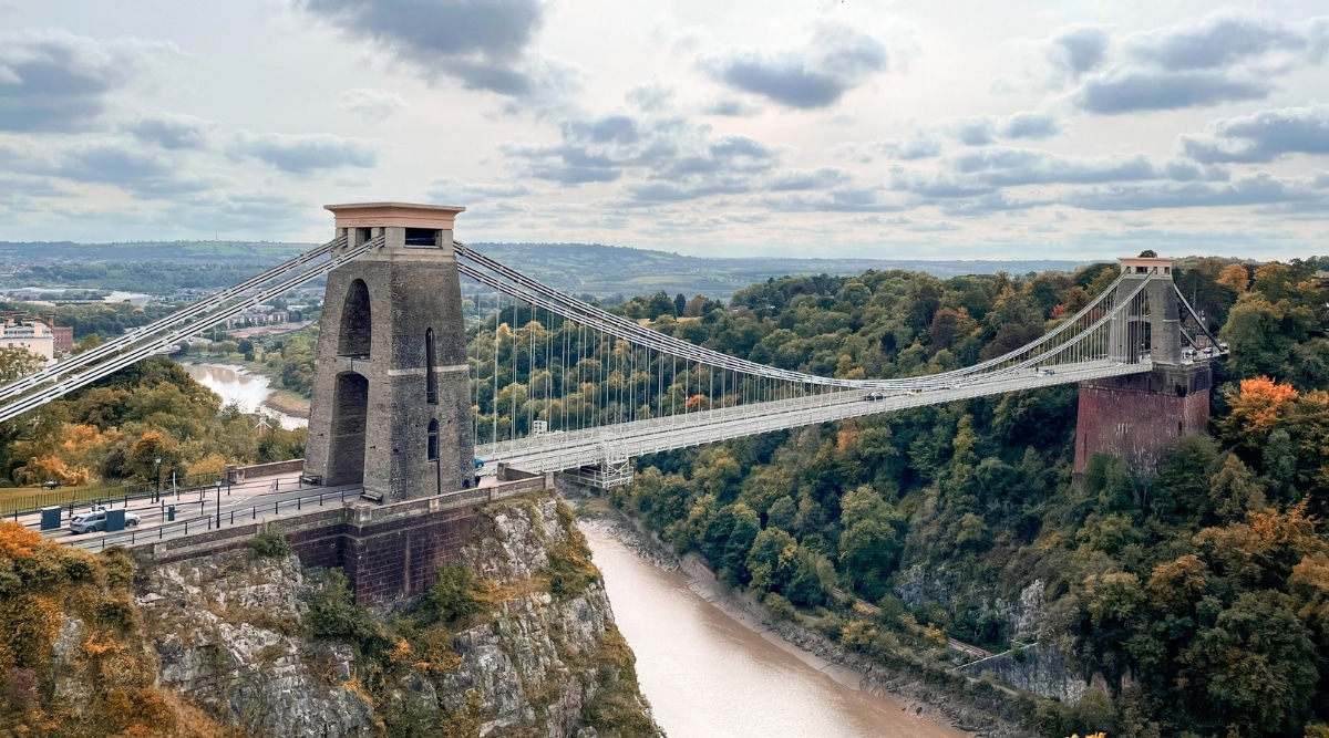 A photograph capturing the Bristol Clifton Suspension Bridge in the United Kingdom. The image presents the iconic suspension bridge spanning the Avon Gorge. The architectural structure features prominent towers and cables, with the landscape of Bristol in the background.