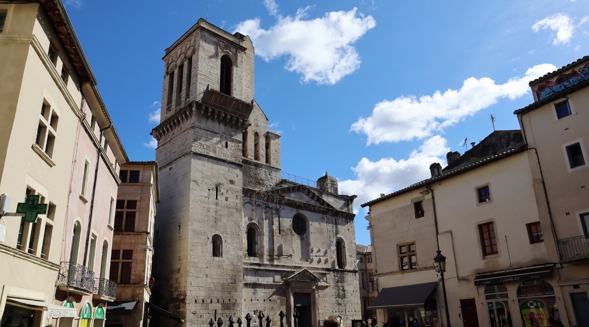 A photograph capturing Cathedral de Nimes in France. The image features the cathedral's exterior architecture, showcasing its prominent facade and distinctive design elements.