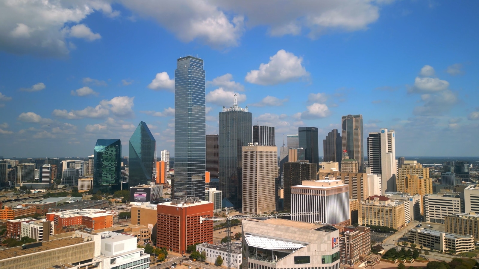 An image capturing the cityscape of Dallas, Texas, characterized by prominent red hues. The photograph depicts the city skyline against a clear sky, with red-toned buildings standing out as key features.
