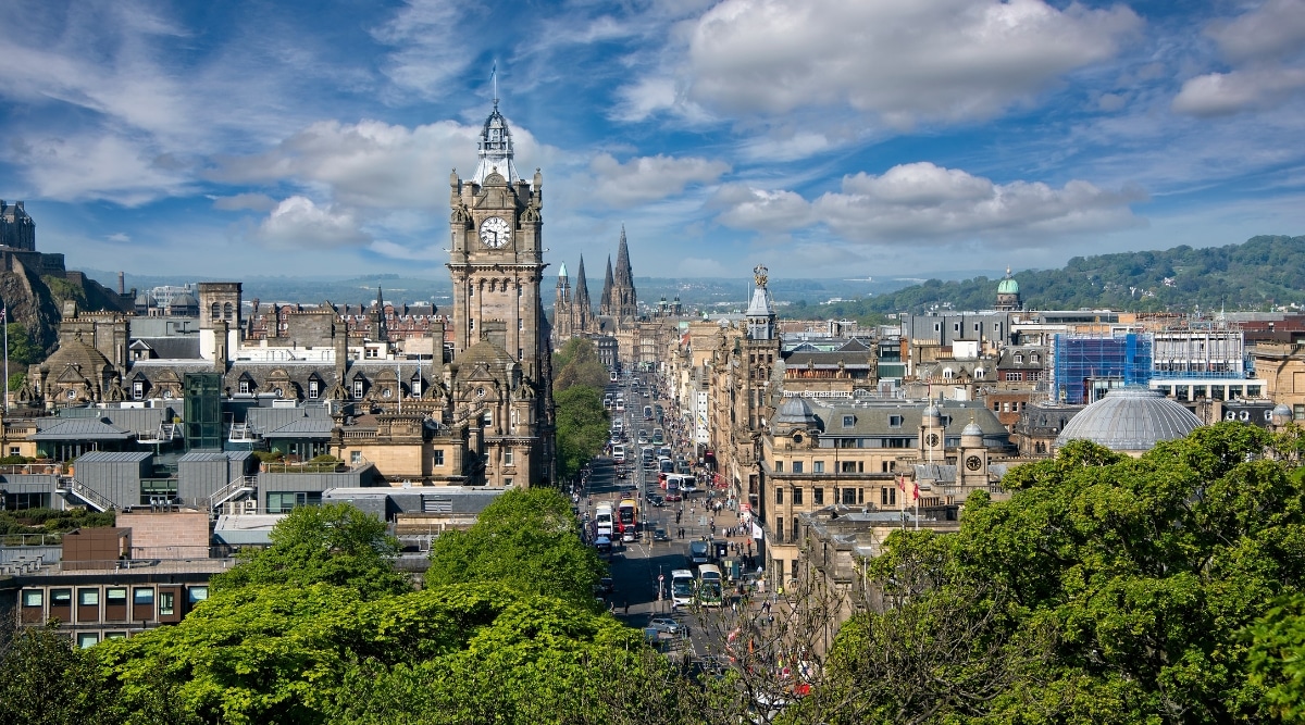 An overhead view capturing Princes Street, a prominent thoroughfare in the city of Edinburgh. The image showcases the linear layout of the street. The street appears busy, with vehicular and pedestrian traffic indicating its role as a central artery for urban movement.