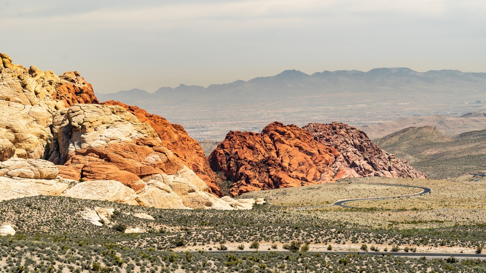 A photograph capturing Red Rock Canyon against a clear sky. The image showcases the distinctive red rock formations and the arid desert landscape synonymous with the conservation area.