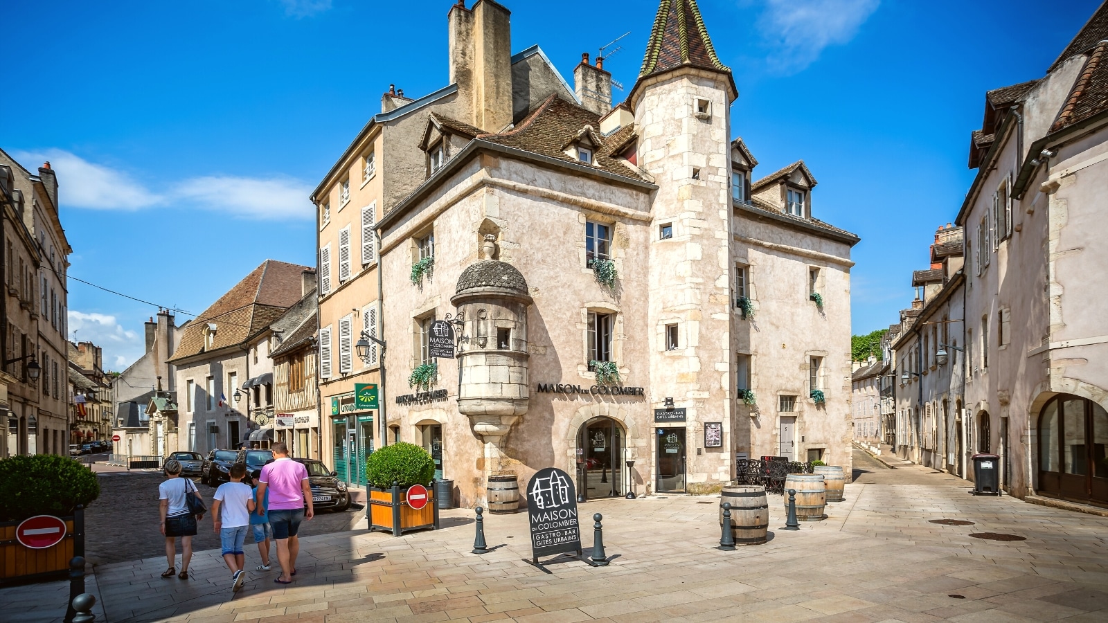 An image depicting La Maison du Colombier in Beaune, France. The photograph captures the exterior of the building with its distinctive architectural features. The structure is situated against a clear sky, showcasing its presence in the urban landscape. 