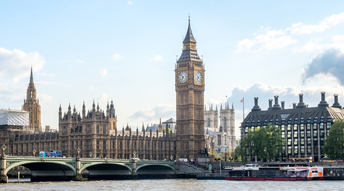 A photograph depicting Big Ben, the iconic clock tower in London, England. The image showcases the renowned structure along with surrounding historic buildings under a cloudy sky.