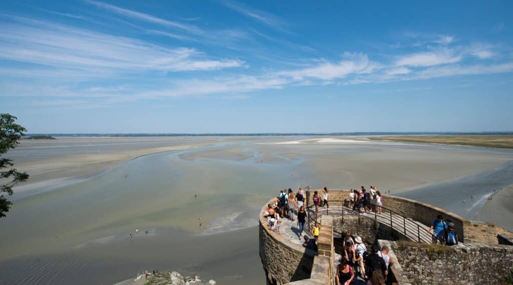 A crowd of tourists overlooking the views at low tide from the monastery up on Mont Saint Michel in France.