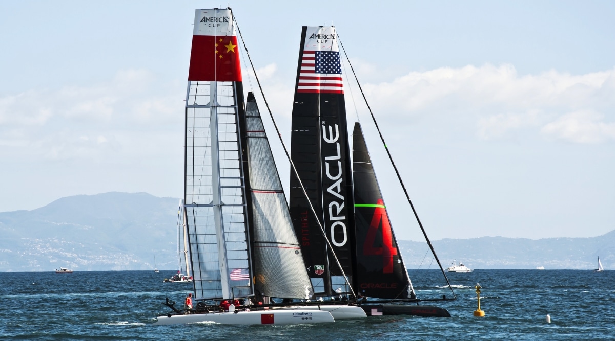 Two competing sailboats racing across a course in the San Francisco Bay.  One Represents the United States and the other represents the Chinese teams.
