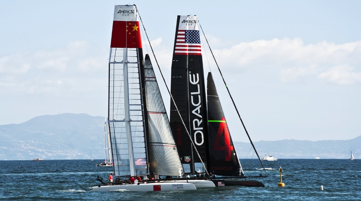 Two competing sailboats racing across a course in the San Francisco Bay. One Represents the United States and the other represents the Chinese teams.