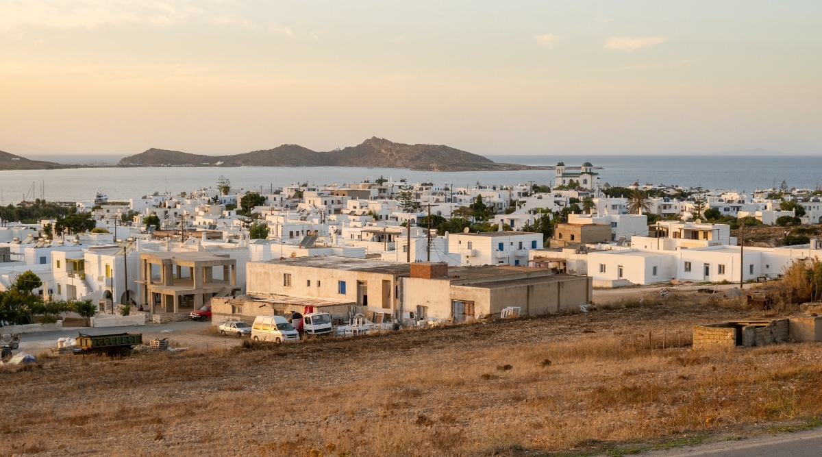 A panoramic view capturing the scenic Naoussa town on Paros Island in the Cyclades, Greece, Europe. The image showcases the town's architecture, coastline, and surroundings. The buildings exhibit the characteristic Cycladic style against the backdrop of the Mediterranean landscape. The harbor area is visible, suggesting maritime activities and waterfront establishments.