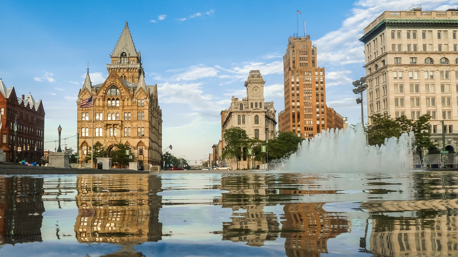 A photograph depicting the Syracuse Saving Bank Building at Clinton Square in Syracuse, New York. The image captures the architectural features of the building, showcasing its design against the urban backdrop. The structure stands prominently within the cityscape, characterized by classic elements reflective of its historical significance.