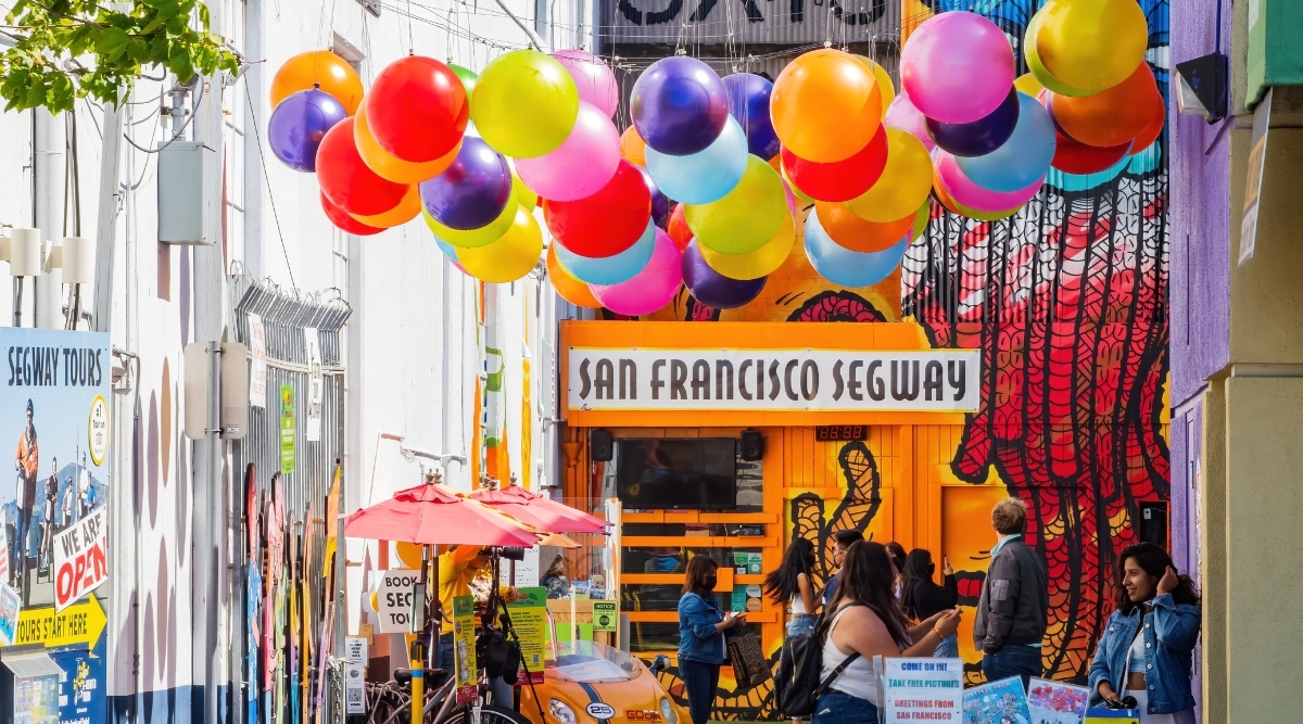 Umbrella Alley full of tourists admiring the arts under a canopy of brightly colored balloons.