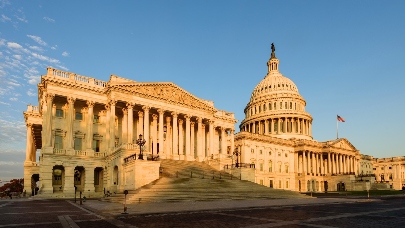 A photograph depicting the Capitol building against a clear morning blue sky. The image emphasizes the iconic architectural structure, serving as the seat of the United States Congress. The neoclassical design of the building is prominent, with the dome and columns standing out against the sky.