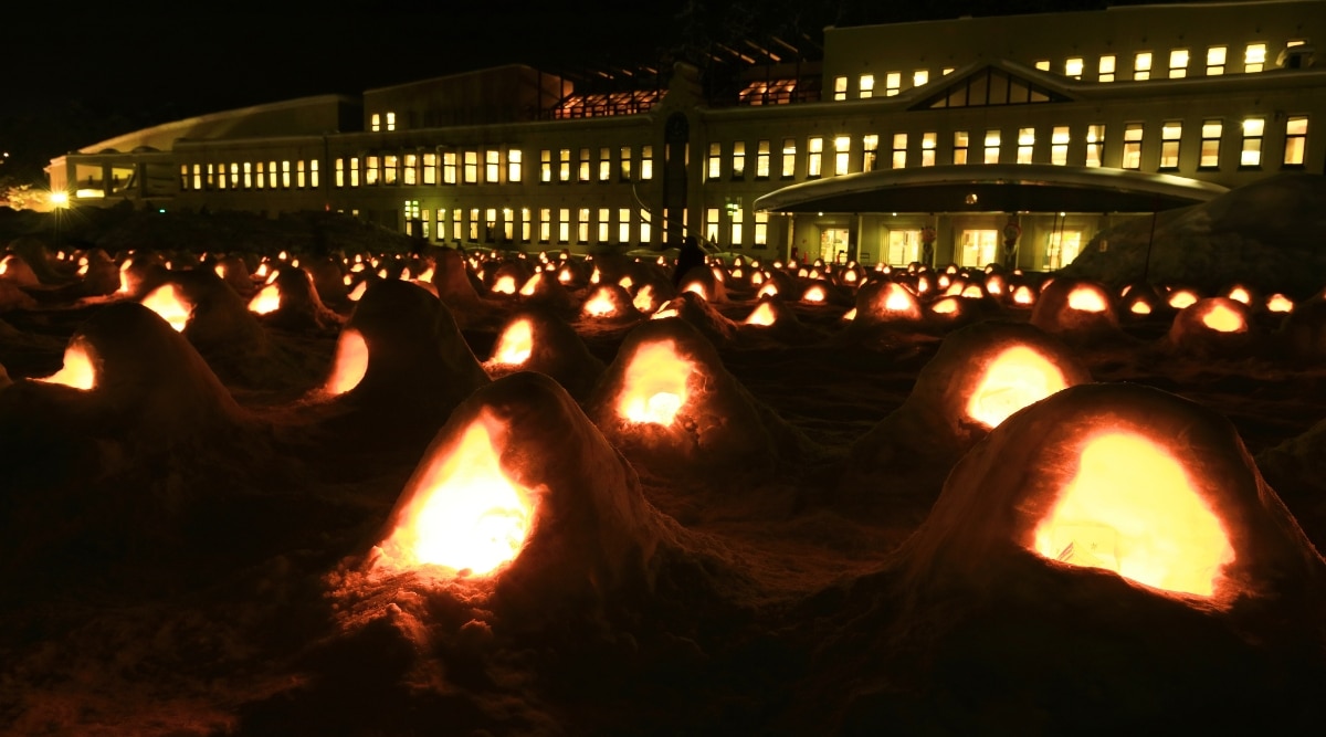 A photograph capturing the Yokote Kamakura Festival, an annual event in Yokote City, Japan. The image features traditional snow huts known as 'kamakura,' arranged in a snowy landscape.