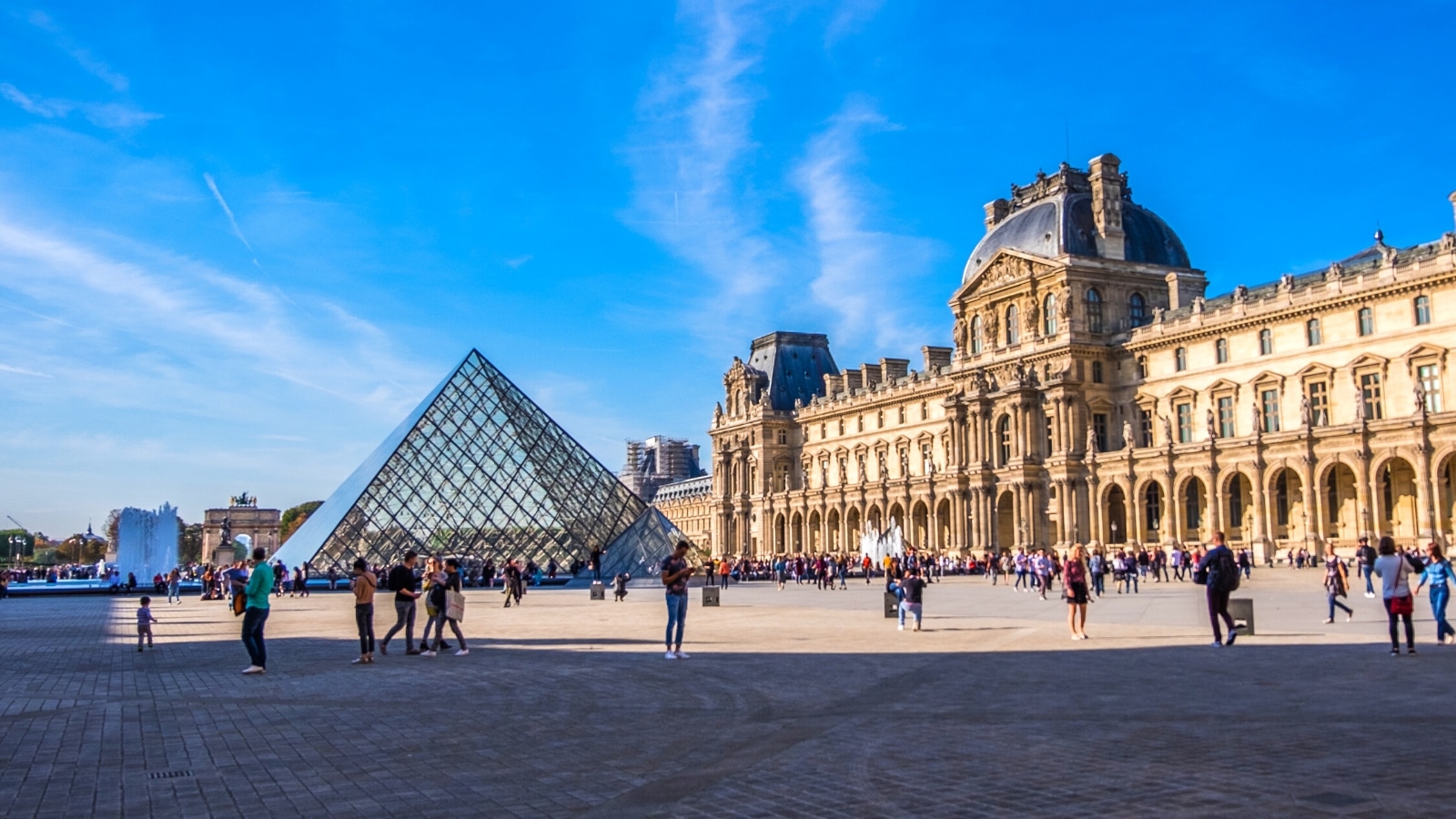 An extensive view of the Louvre on a bright sunny day. The sky is blue and clear, providing a backdrop to the Louvre