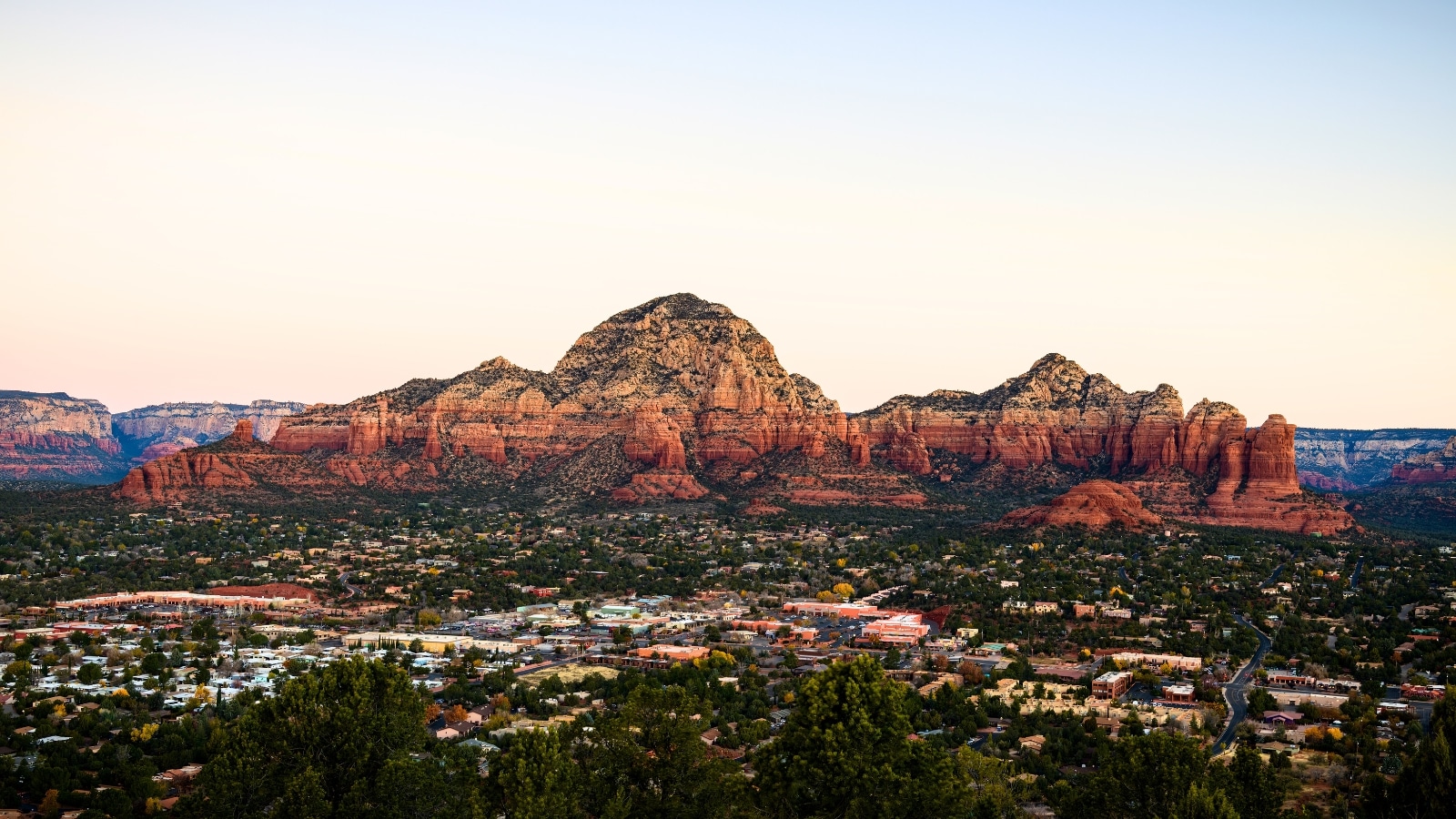 A photograph capturing Capitol Butte and Coffee Pot Rock formation, as viewed from Airport Mesa overlooking the town of Sedona, Arizona, USA. The image depicts the prominent rock formations against the desert landscape.