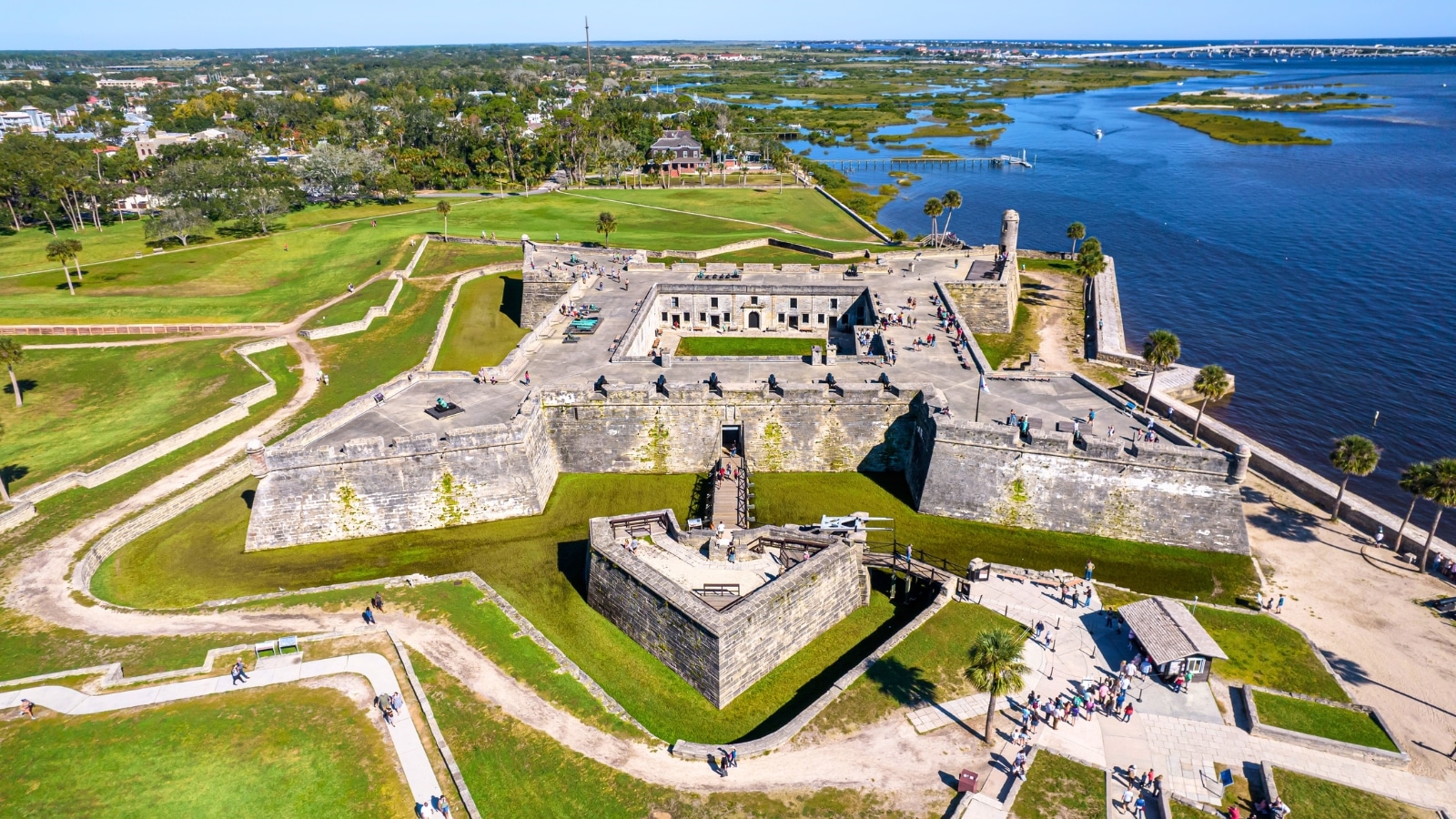 An aerial view capturing the Castillo de San Marcos National Monument in St. Augustine, the oldest town in the USA. The image showcases the historical fortification against the backdrop of the town's landscape. The castle's distinctive architectural features, including its stone walls and bastions, are visible in the photograph.