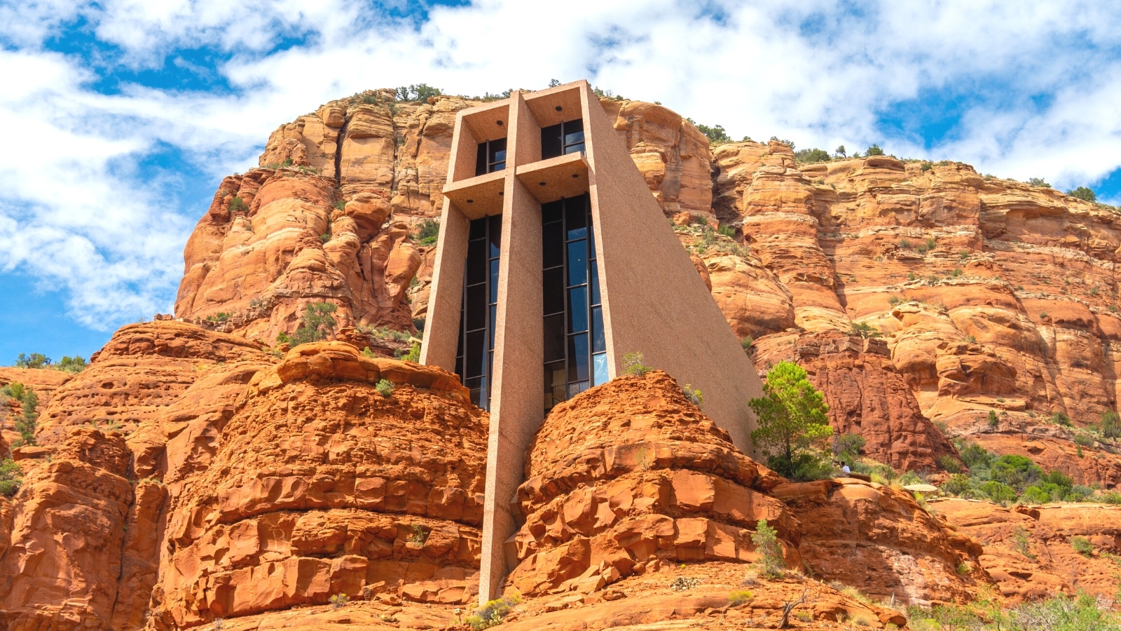 A photograph showcasing the Chapel of the Holy Cross, a religious landmark located in Sedona, Arizona. The image depicts the chapel's unique architectural design, characterized by its modernist style and incorporation into the red rock formations of the surrounding landscape. The chapel's exterior features clean lines and minimalistic elements.
