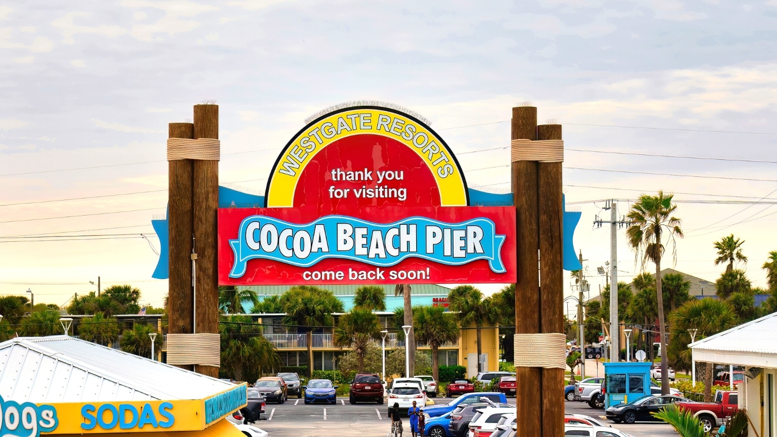 A photograph featuring a bright sign at the entrance of Cocoa Beach Pier, prominently displaying the words 'Cocoa Beach Pier.' The sign stands out against the backdrop, with clear visibility and legible lettering.