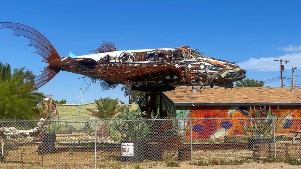 The da Vinci Fish at Bombay Beach Biennale is a captivating art installation inspired by the ingenuity of Leonardo da Vinci and the aquatic world. Crafted from reclaimed materials, the da Vinci Fish features intricate metalwork resembling the scales and fins of a fish, while its elongated form mimics the graceful movement of marine life. The sculpture's shimmering surface reflects the desert sunlight, creating a mesmerizing interplay of light and shadow.