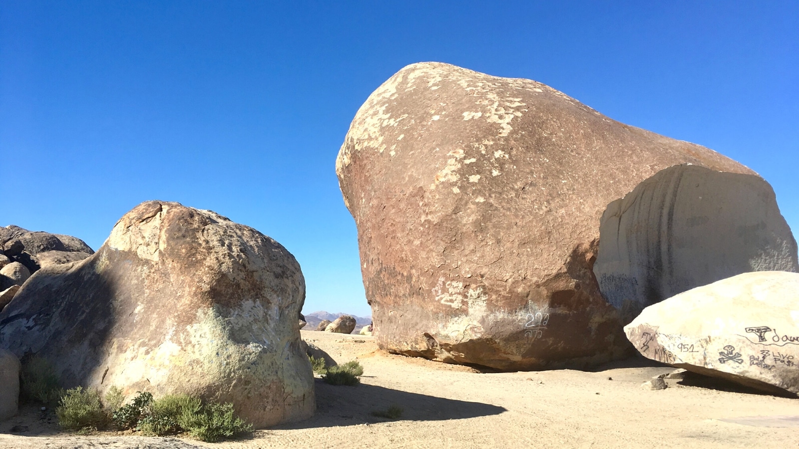 An image capturing Giant Rock in California, situated in an arid landscape. The photograph features a vast stone formation notable for its significant size.