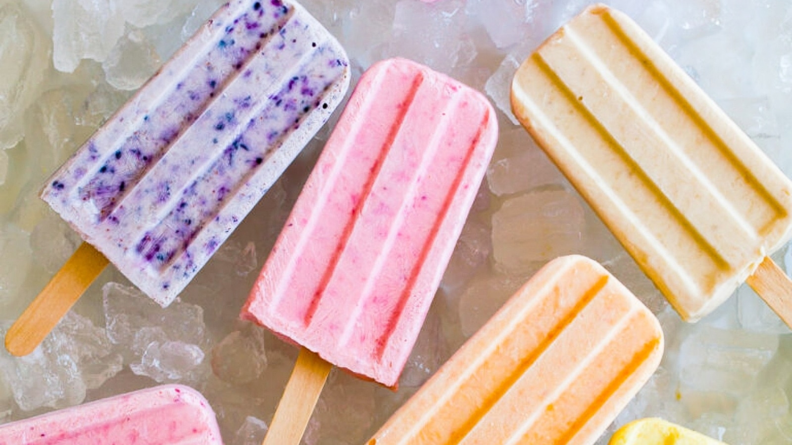 The image features several colored popsicle ice creams lying on a bed of ice, presenting a refreshing and summery scene. The popsicles showcase vibrant colors.