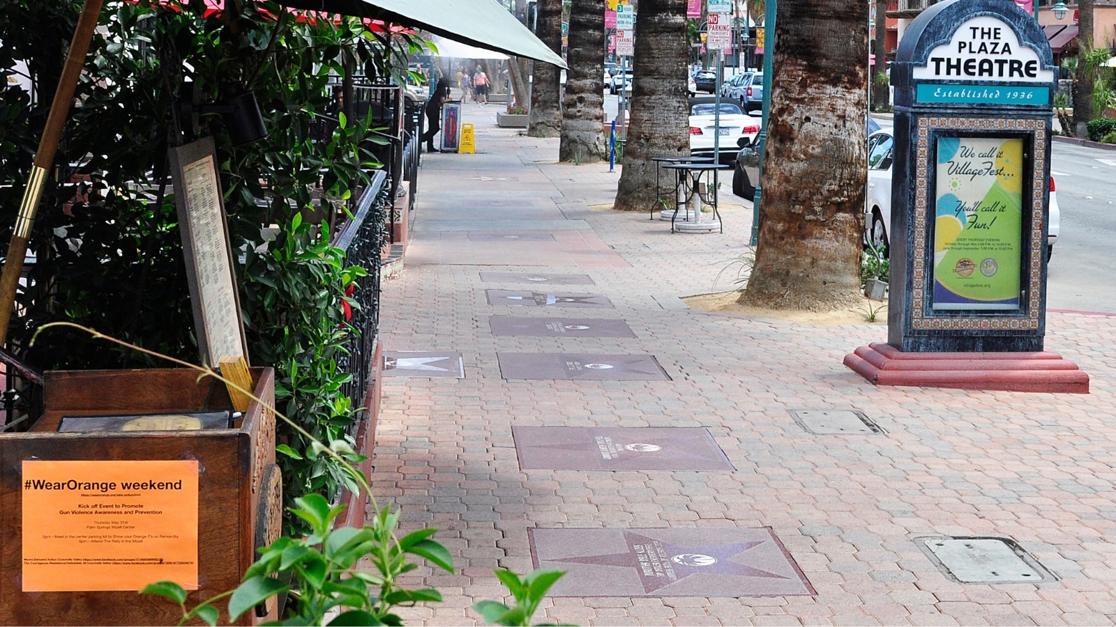A city street view featuring the Palm Springs Walk of Stars. The image showcases square tiles embedded in the sidewalk, each adorned with stars and signatures.